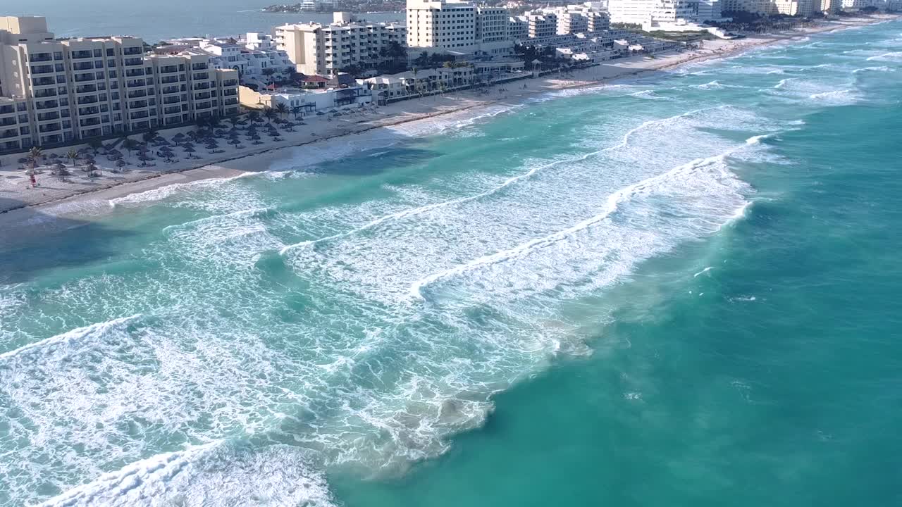 在夏季和阳光明媚的日子里，坎昆酒店区海滩的广角航拍，无人机拍摄的海浪和蓝绿色的海水视频素材