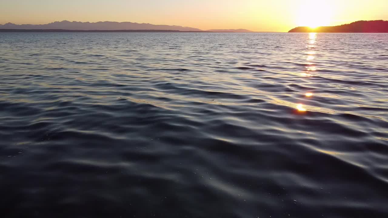 华盛顿州日落时分，无人机在普吉特海湾的海浪上低空飞行视频素材