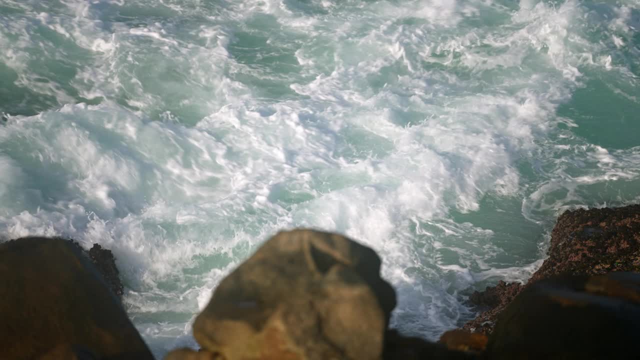 碧绿的海浪冲击着崎岖的海岸。崖顶俯瞰着动态的海洋，岩石承受着不断的汹涌。狂暴的大海的能量，溅在海岸上，在空气中有强烈的浪花。原始的海洋场景，元素。视频素材