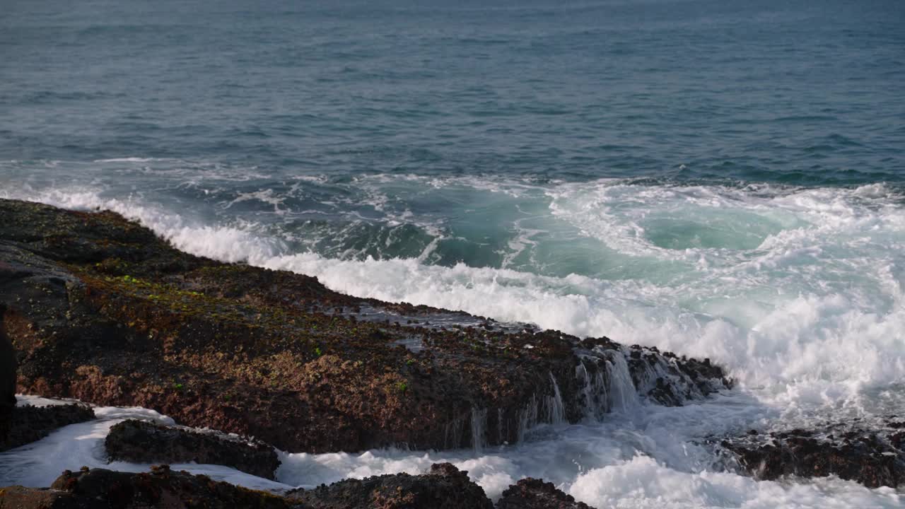 汹涌的海浪冲击着岩石海岸。沿海风光与泡沫潮汐，海洋的力量显示。电影观自然气候研究，生态旅游推广，休闲内容，库存素材。视频素材