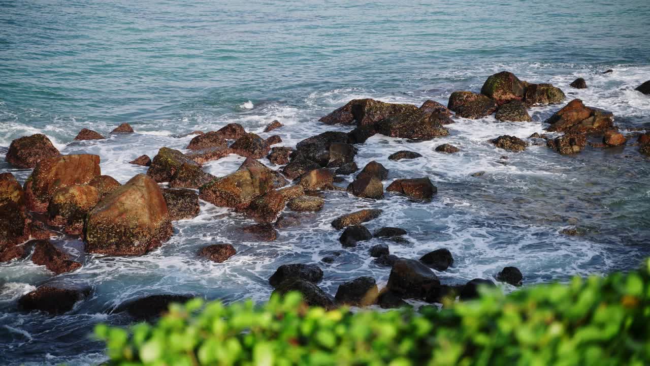 汹涌的海浪冲击着崎岖的岩石，浪花笼罩着空气，沿海的海景伴随着泡沫般的潮汐，戏剧性的自然现象，海景捕捉着海洋的力量。热带景色描绘了大自然的壮丽视频素材