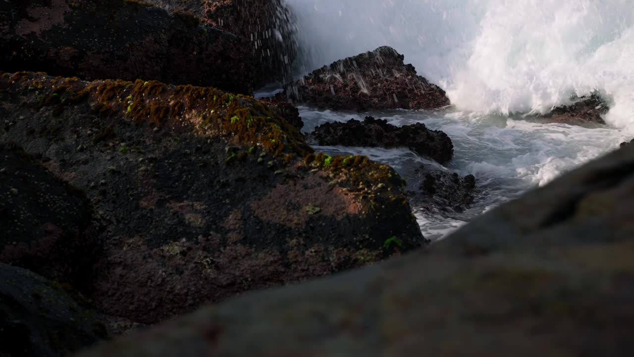 汹涌的海浪拍打着崎岖的海岸线岩石。海水喷溅，大海怒吼，海岸风光自然光。动态海景捕捉大自然的力量在阳光明媚的日子。视频素材