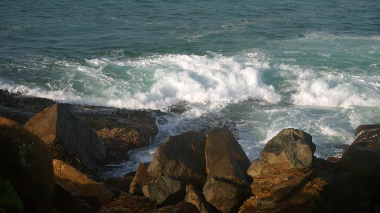 海浪冲击着海岸线上崎岖的岩石。动态海洋涌动，海岸景观一览无余。自然的海景，强大的海浪冲击，宁静的海岸风光。海洋环境，多岩石海岸。视频素材