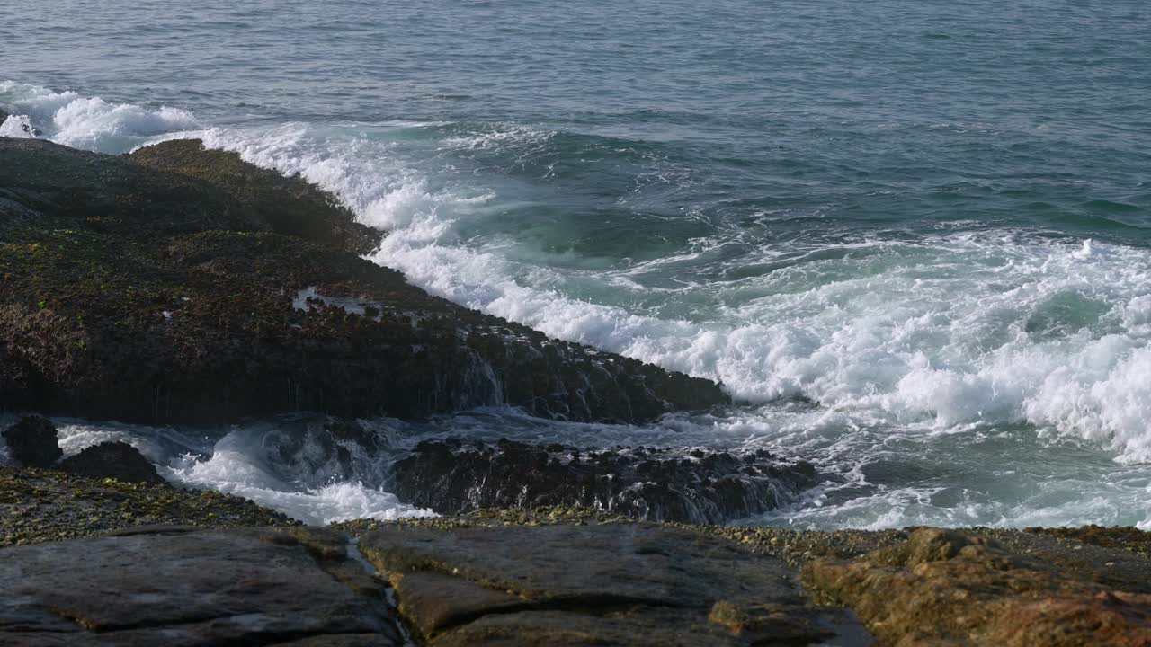 海浪冲击着岩石海岸。动态的海水溅在巨石上，形成泡沫。自然的海边氛围，强大的海浪，海滨景观。没有人，宁静的自然风光，海边的镜头。视频素材