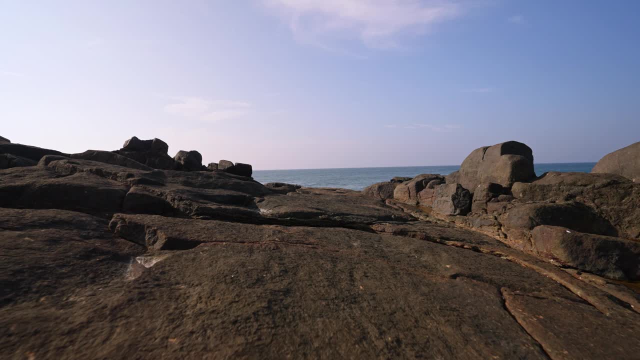 海岸景观，宁静的海浪冲刷着风化的岩石。海边风光怡人，氛围怡人。沿海岩层通向平静的海水，是和平内容的理想选择。视频素材