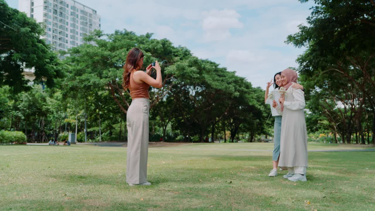 友谊的快照:不同的女性朋友用紧凑型相机在公园漫步视频素材