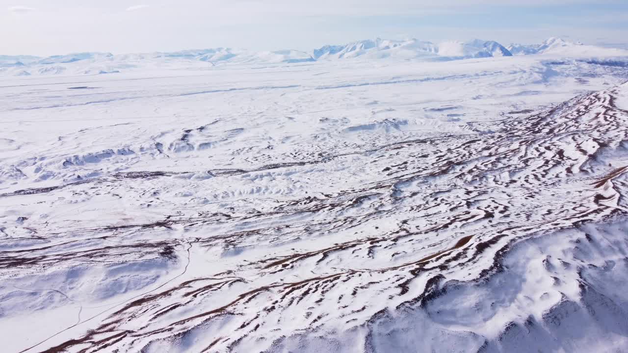 在多云的蓝天下，无人机拍摄的白雪皑皑的山顶视频素材