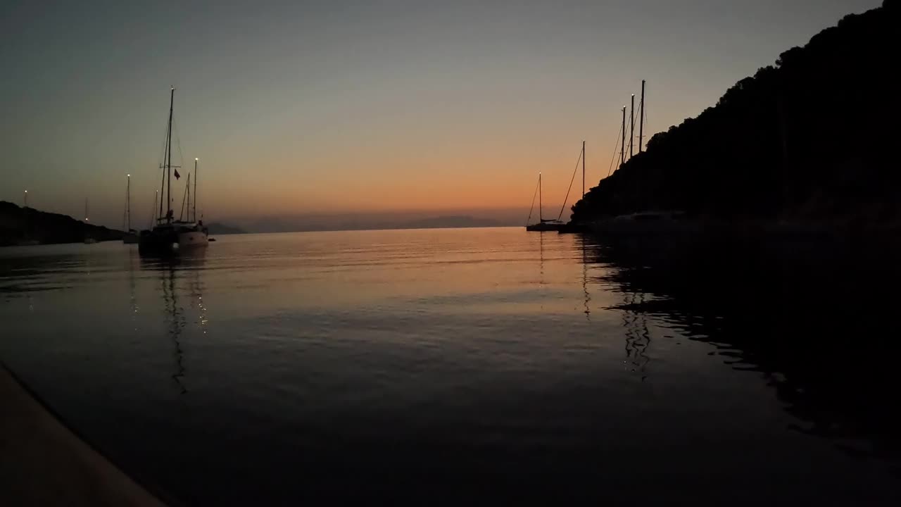 地中海岛屿海湾上的日出，周围停泊着许多帆船和游艇视频素材