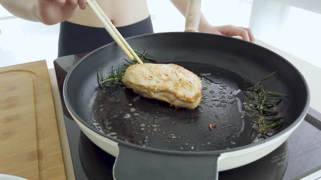 近景:有人在铁锅上撒肉调料，用大蒜和莳荽炒鸡胸肉视频素材