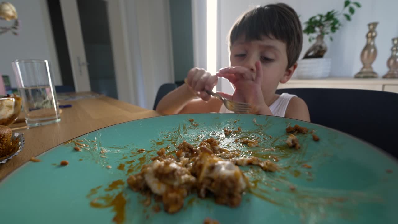 吃午餐的小男孩在餐桌上使用叉子视频素材