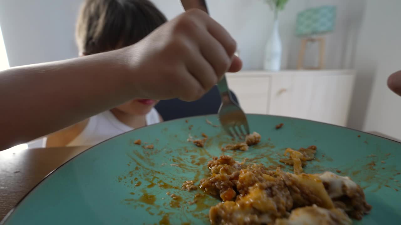 一个小男孩在吃饭，孩子在午餐时间用叉子。快乐的孩子吃东西视频素材