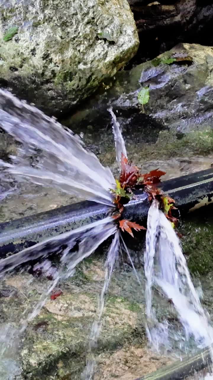 漏水管道突水，环境问题凸显。石头间水管问题的封闭。管道泄漏，紧迫的环境问题和水资源浪费问题视频素材