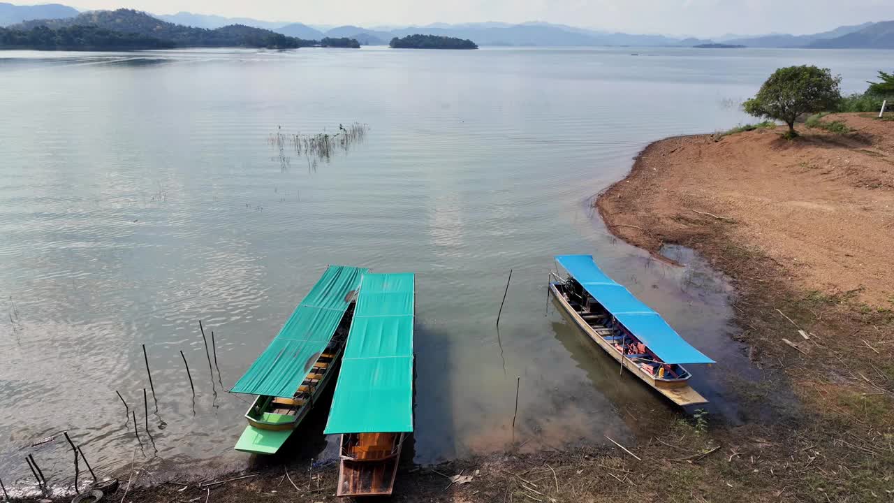 三艘船停靠在湖岸上，阳光明媚的一天，蓝天白云映衬在泰国的噶叻山国家公园。视频下载