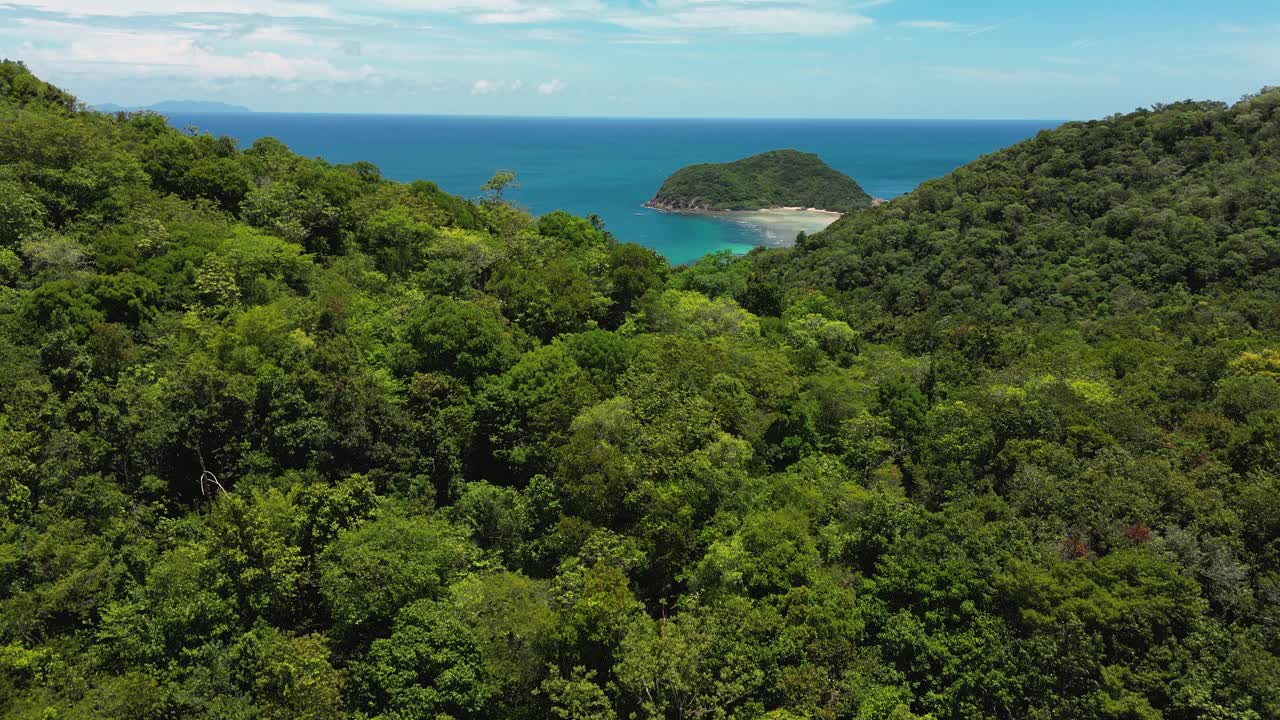 热带海岸线与清澈的水显示在郁郁葱葱的山，空中上升视频素材