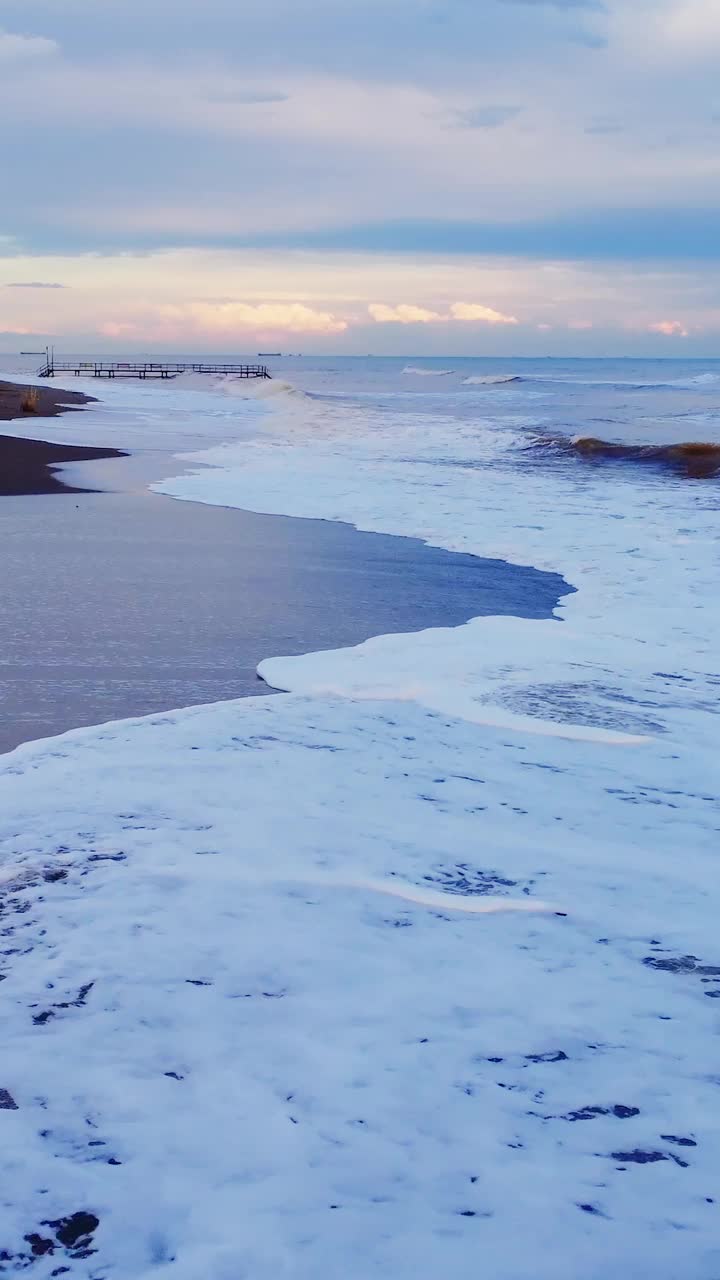 地中海的黄昏:无人机捕捉到海滩傍晚的魅力。黄昏的海滩，海浪与沙滩相遇，背景是城市。黄昏，海滩和城市灯光:自然与城市美景的完美融合视频素材