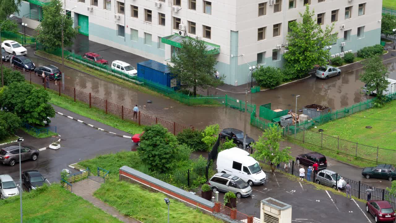 市中心房屋间狭窄道路上的一个大水坑。人们爬上篱笆越过水坑视频下载