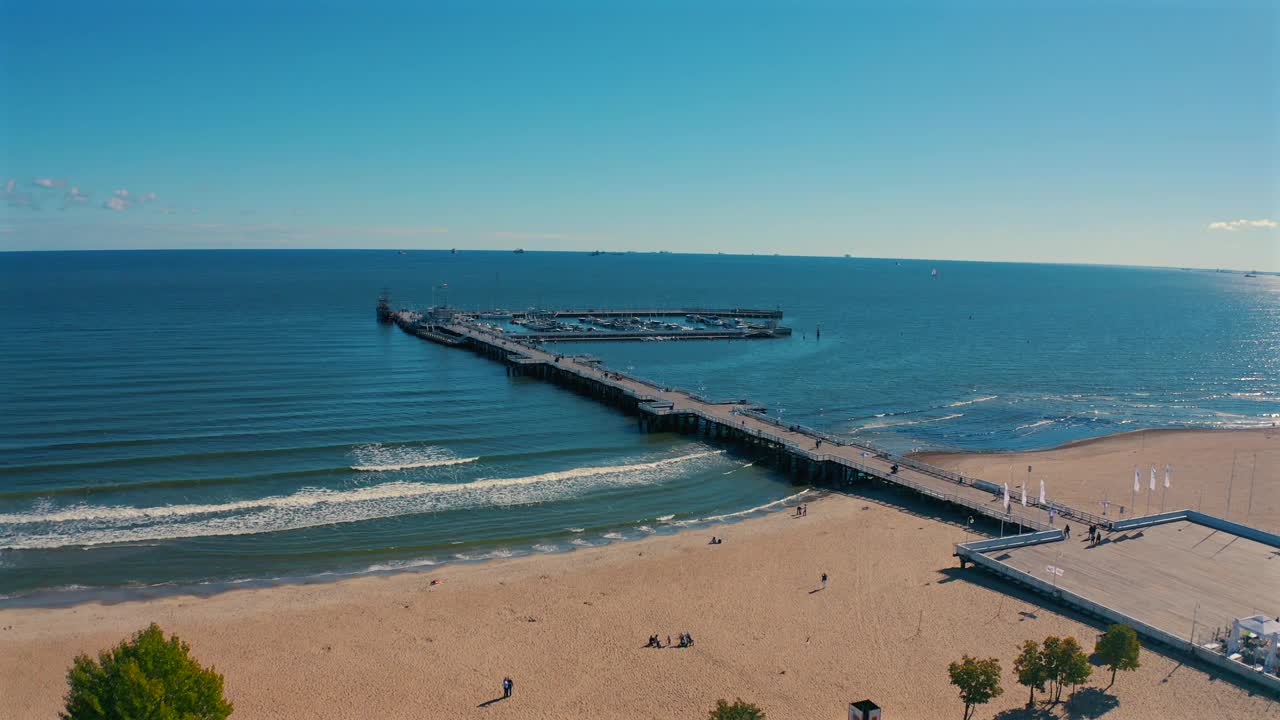 无人机飞向码头，海浪涌向海滩和天空视频素材