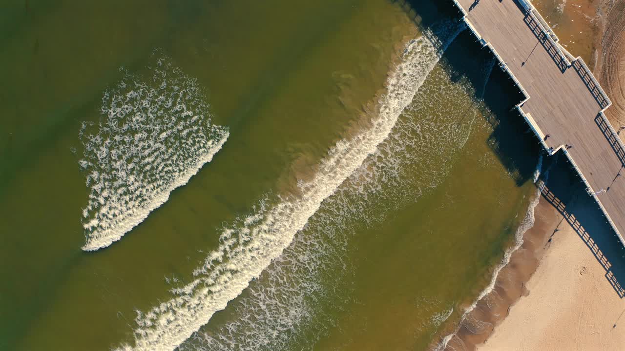 鸟瞰码头，海浪涌向海滩视频素材