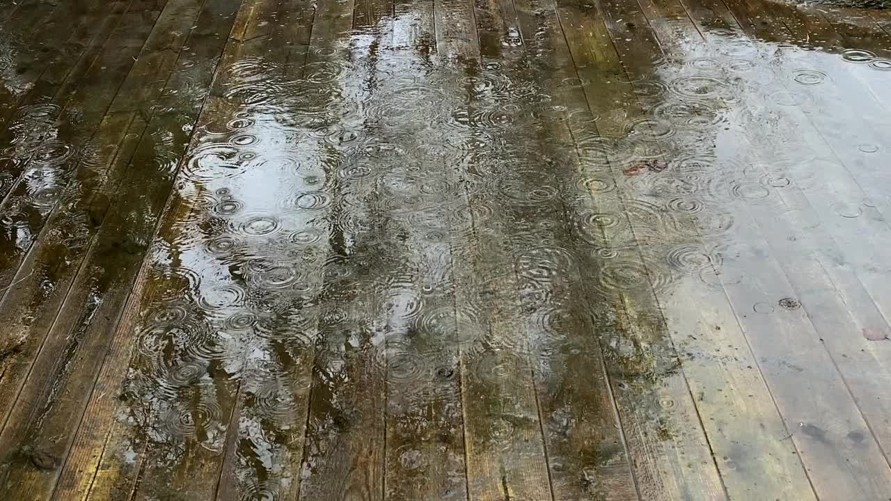 大雨淋在露台上的旧木甲板上。瑞典乡村的春夏雨。视频下载