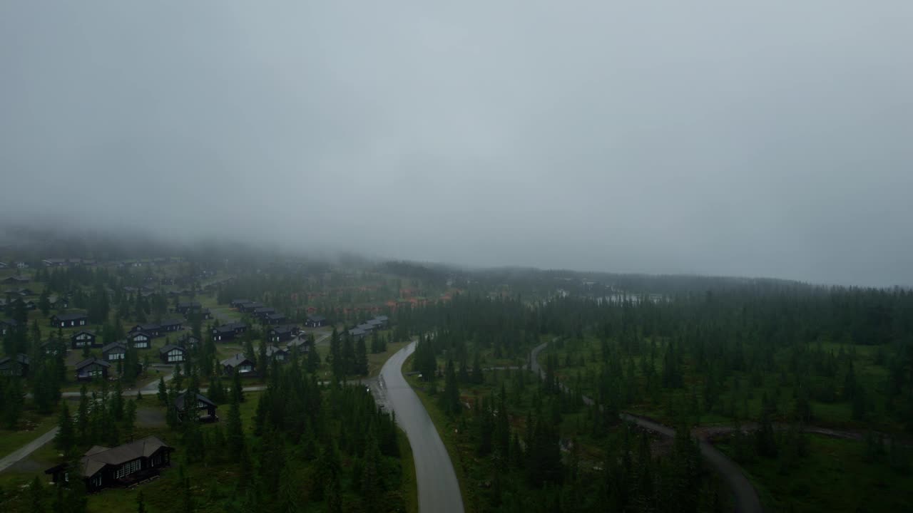 在挪威的一个滑雪胜地，在布满松树和豪华木制度假平房的迷雾山路上飞行视频素材