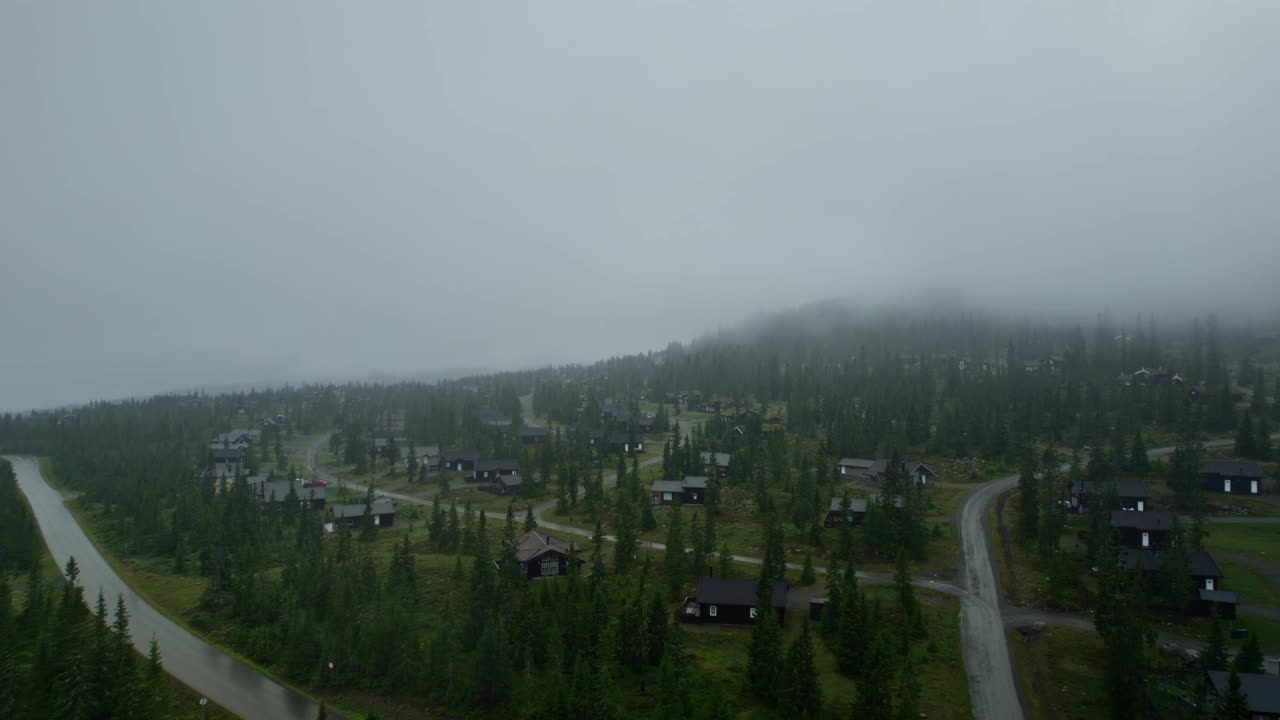 在挪威薄雾缭绕的山间滑雪胜地，飞过舒适小屋的屋顶视频素材