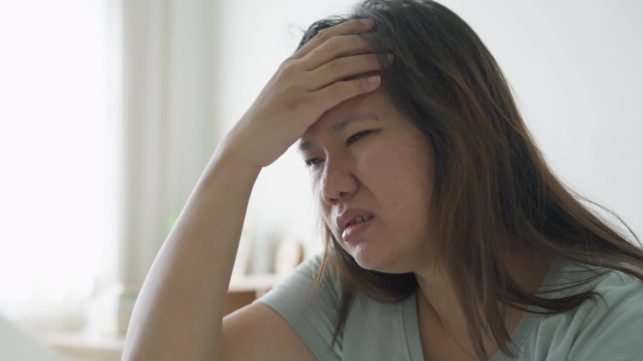 早上醒来后头痛的女人坐在床上视频素材