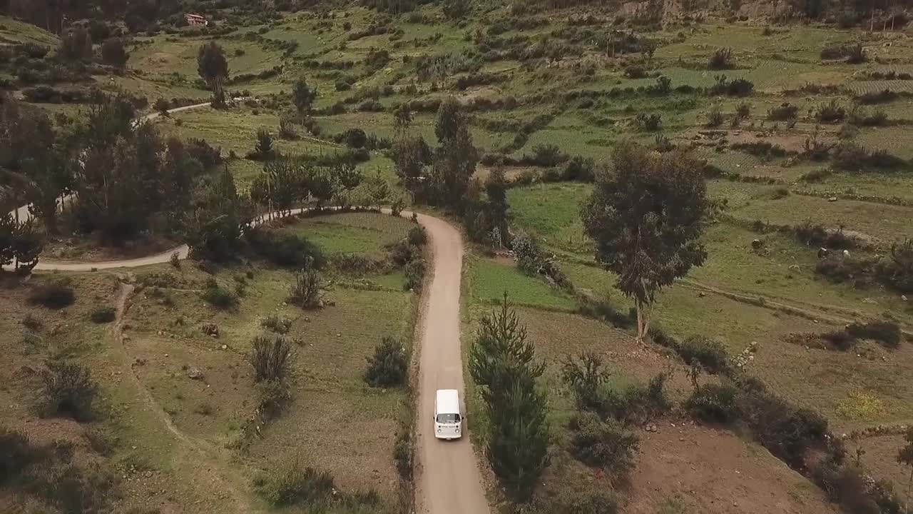 电影的鸟瞰图，一辆面包车行驶通过秘鲁的农田，风景秀丽的驾驶公路之旅视频素材