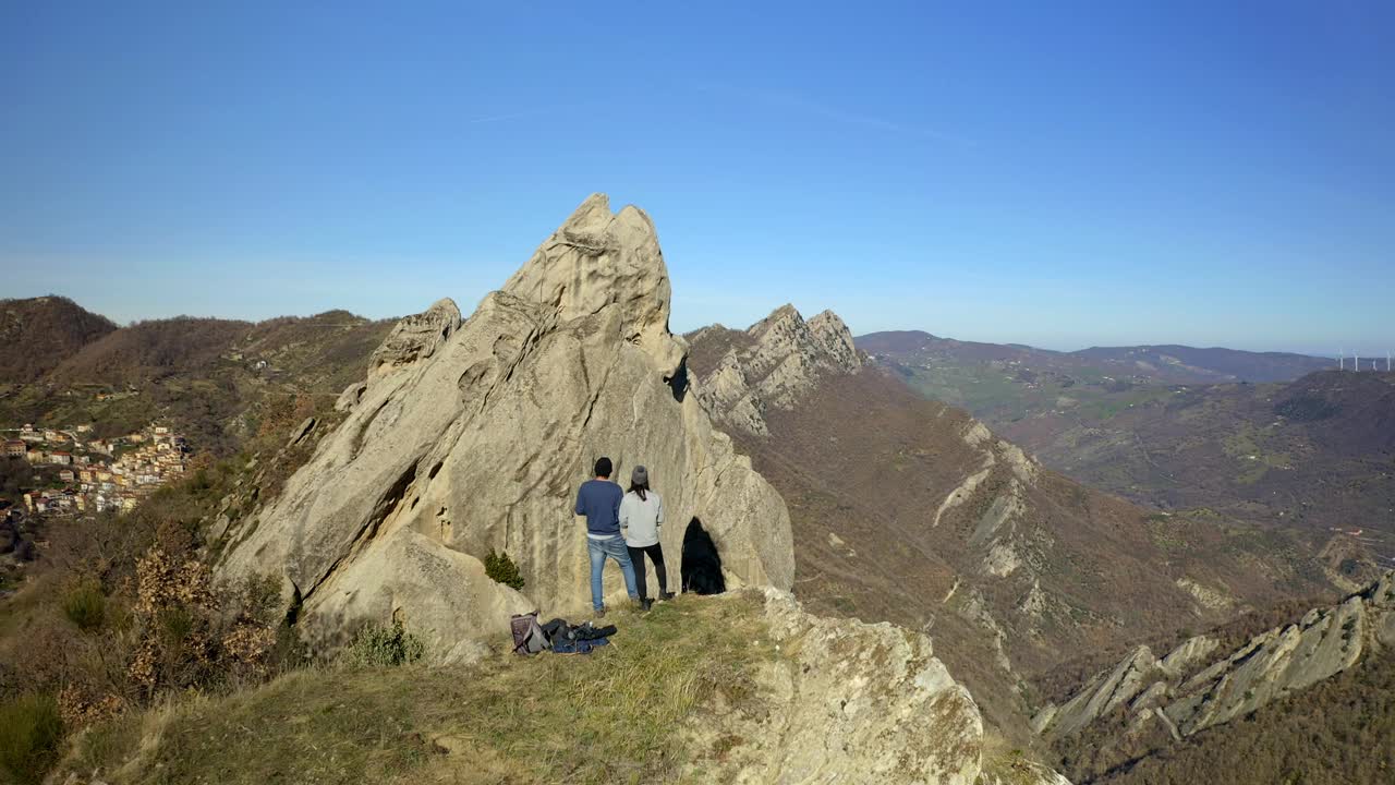 无人机航拍的一对夫妇在意大利波坦察的传统村庄Castelmezzano和Pietrapertosa看岩石视频素材