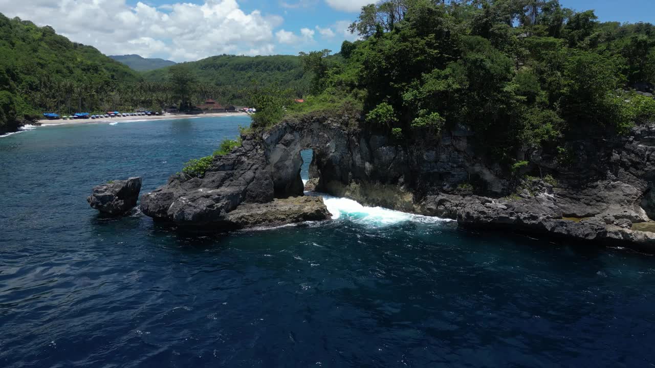 努沙佩尼达岛海岸外的一个孤岛，有岩石拱门和绿色植物，蓝色的海浪拍打着。视频素材