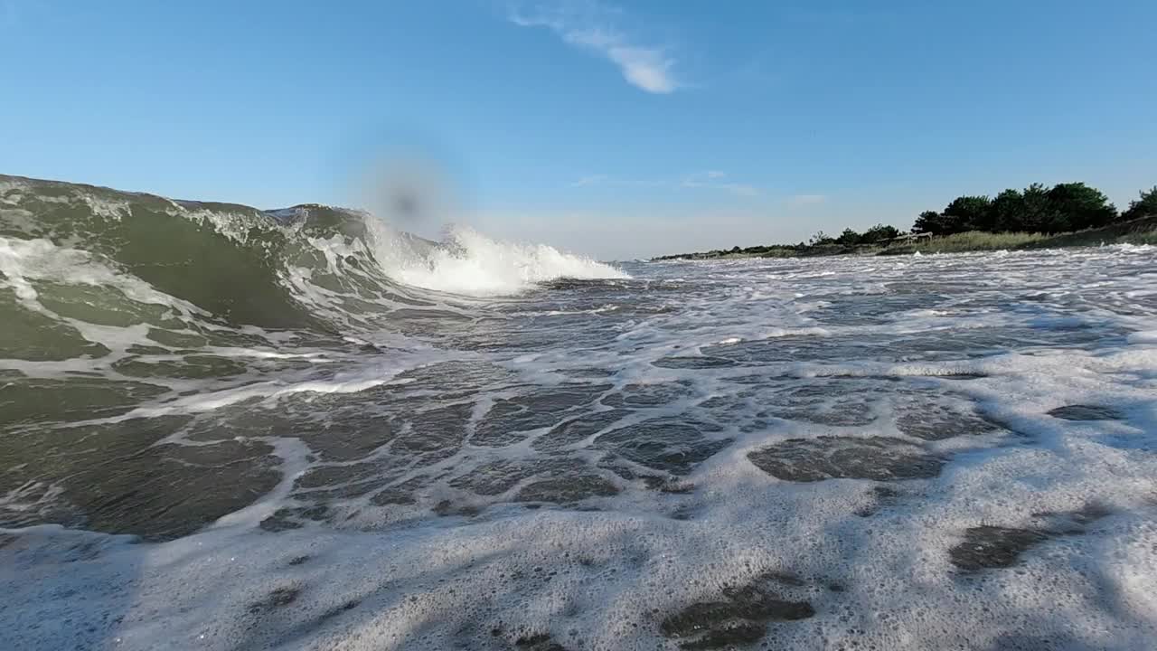 一股海浪冲击着海岸，盖住了摄影师。慢动作视频下载