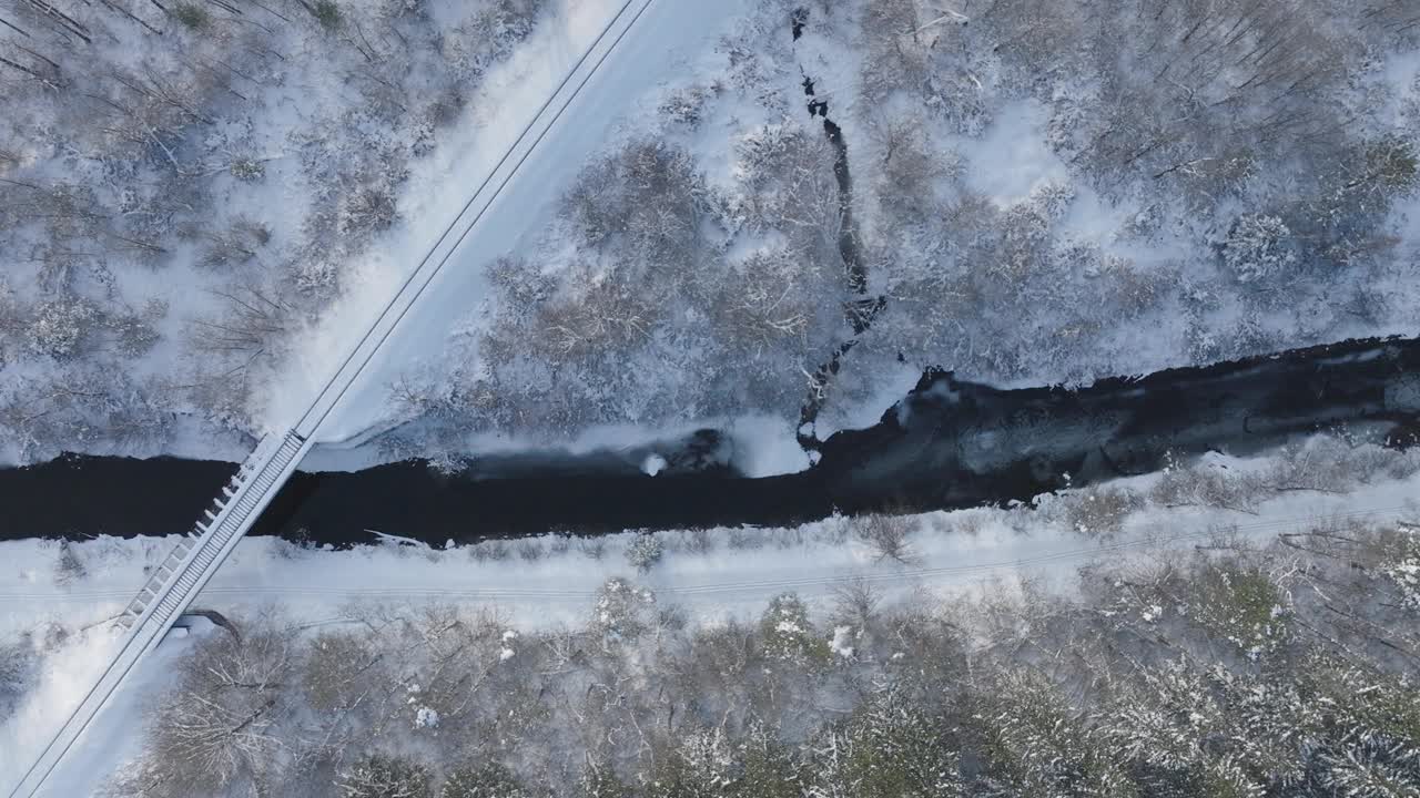 冬季大桥横跨部分结冰的河流，空中俯瞰视频素材