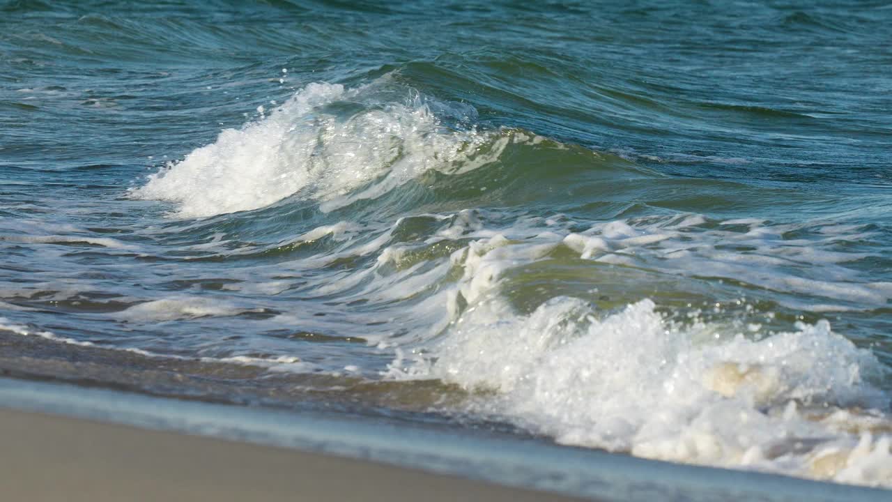 温柔的海浪在海洋一瞥沙滩底部透过清澈的水。视频素材