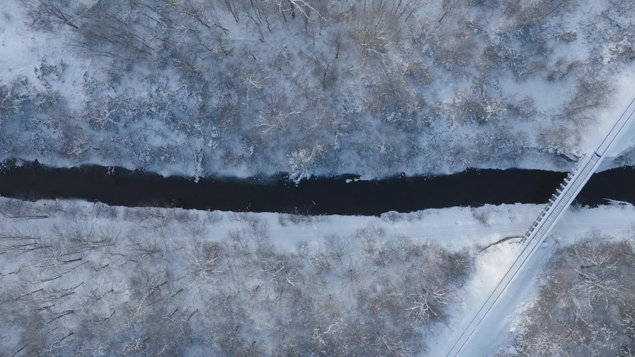 冬季大桥横跨部分结冰的河流，空中俯瞰视频素材