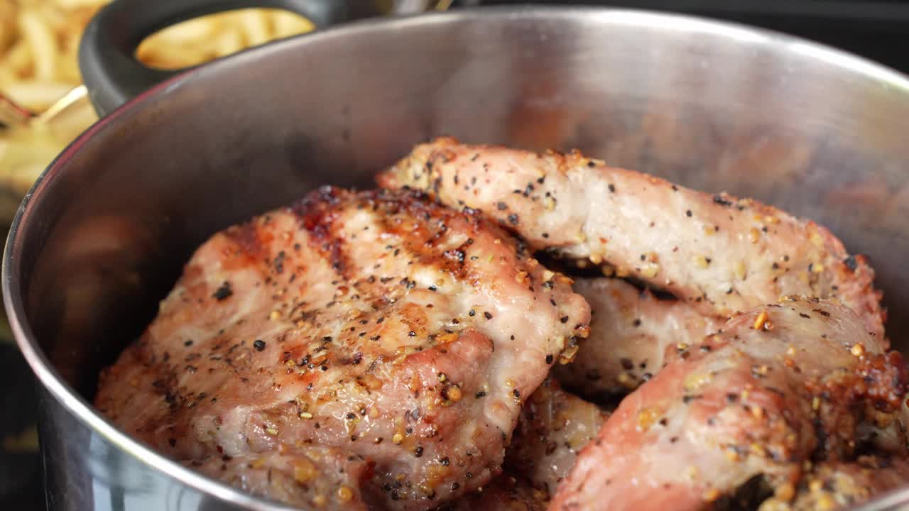 手拿着烤好的烤肉排在不锈钢锅里近距离观看。食品和烹饪概念。视频素材