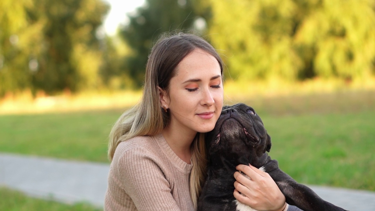 在外面，一名妇女看着一只从收容所收养的黑色法国斗牛犬，紧紧地拥抱着她。帮助无家可归的动物，无子女视频素材