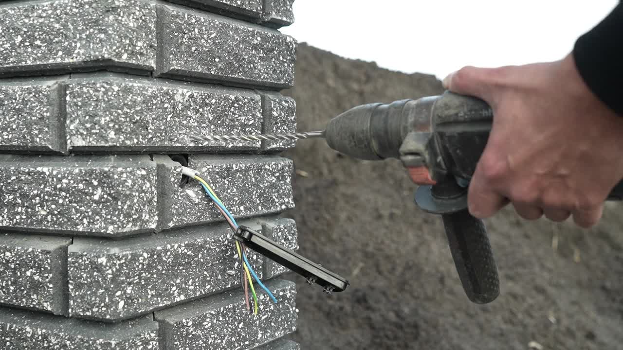 建筑工用锤子在墙上钻一个洞。冲击钻射孔器打孔特写视频素材