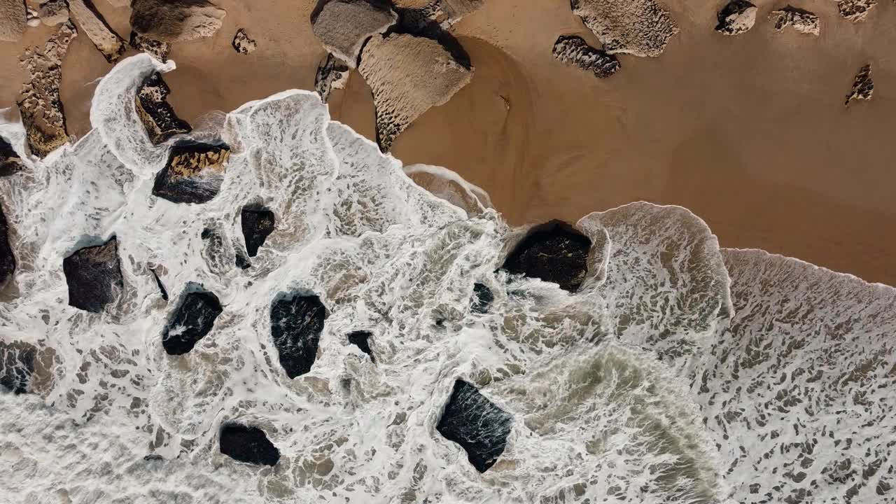 鸟瞰海浪撞击葡萄牙纳扎雷的岩石海滩。拿撒勒的海岸魅力邀请游客欣赏自然与元素之间的和谐。4 k。视频素材