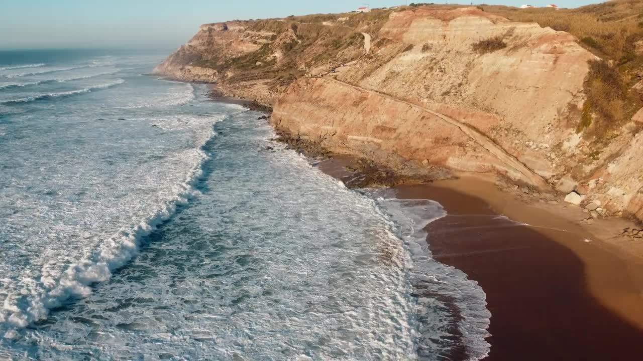 航拍到无情的海浪冲击着葡萄牙崎岖的海岸地区。在波涛与崎岖的海岸线碰撞的地方，有着原始而不可驾驭的海洋力量。旅游和度假的概念。4 k。视频素材