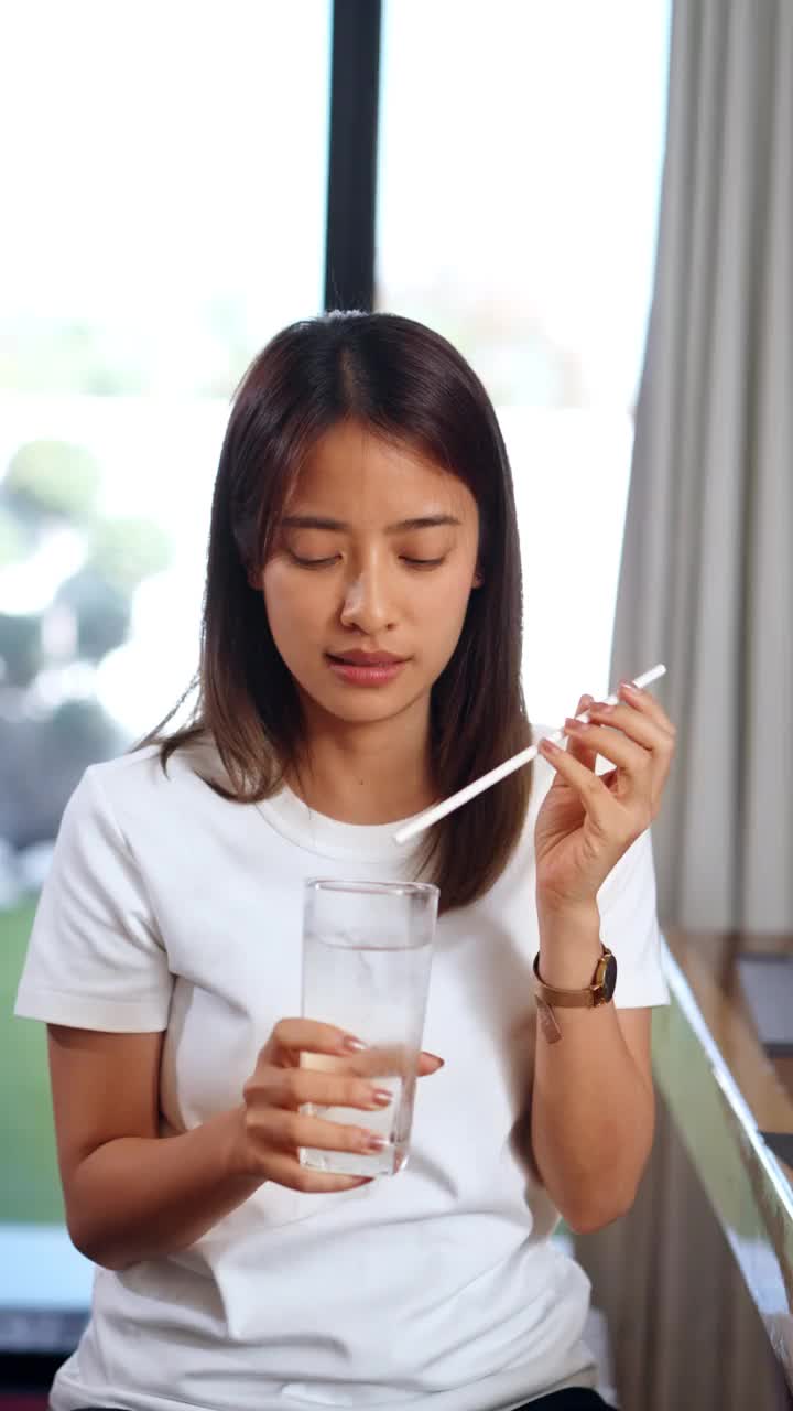 女人坐在餐厅里用吸管喝冰水视频素材