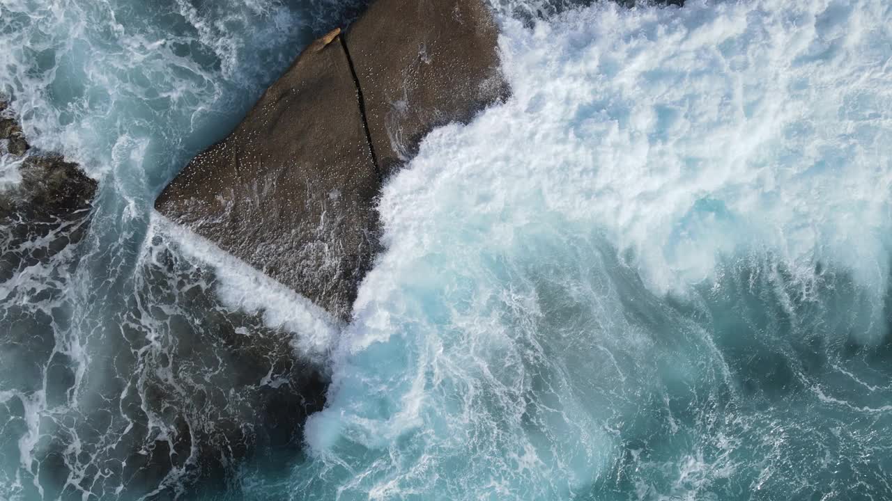 海浪有规律地冲击着岩石海滩视频下载