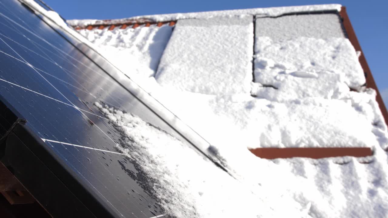 在阳光明媚的日子里，位于私人住宅屋顶的光伏太阳能电池板上的积雪融化视频素材