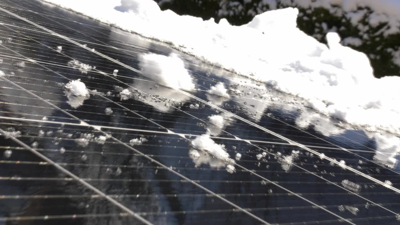 在阳光明媚的日子里，位于私人住宅屋顶的光伏太阳能电池板上的积雪融化视频下载