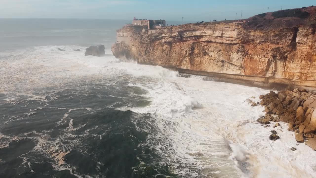 葡萄牙纳扎雷的岩石海滩，海浪汹涌。棕色悬崖夹。视频素材