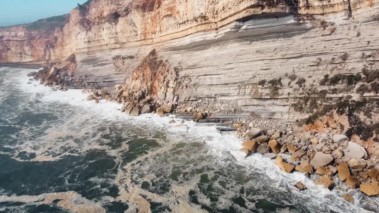 在葡萄牙中部著名的纳扎雷悬崖海岸，航拍汹涌的海水。海浪冲击着海岸线上雄伟的天然岩层。4 k。视频素材