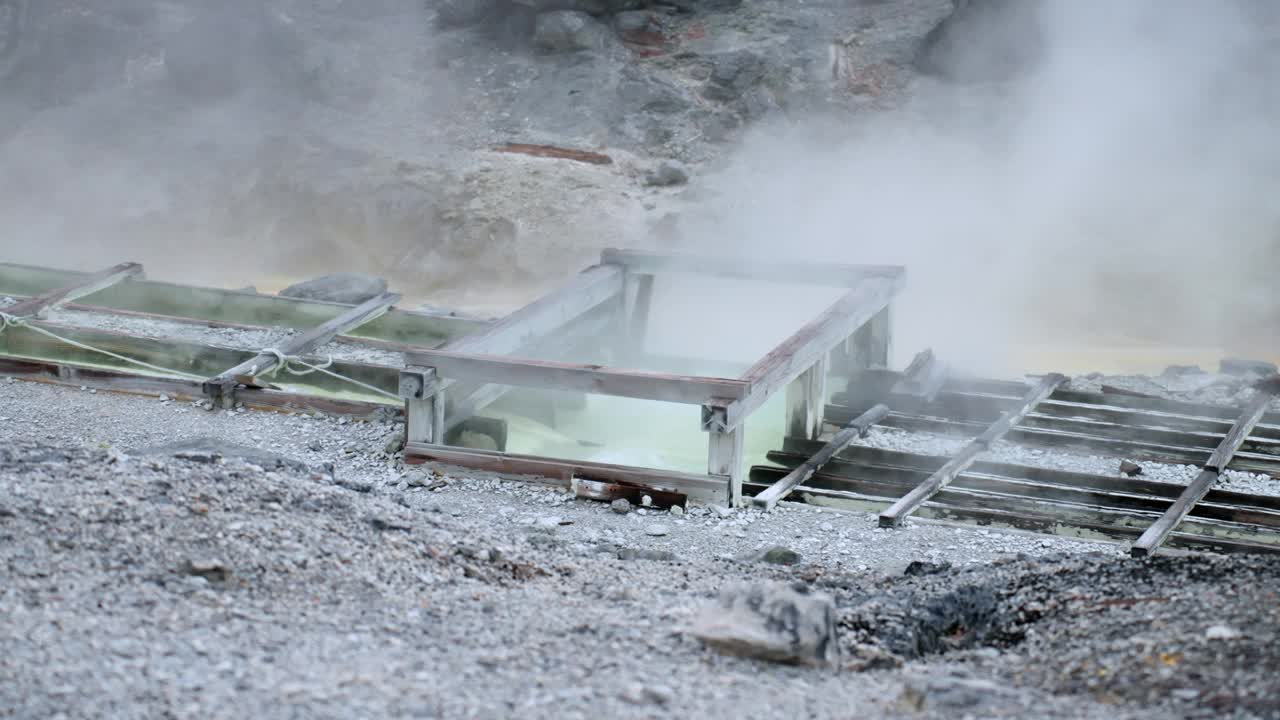 近距离拍摄的蒸汽从温泉附近的岩石山谷在秋田，日本东北。宁静的环境吸引游客在温泉附近放松，享受大自然的美丽，以及古老的硫磺生产过程视频素材