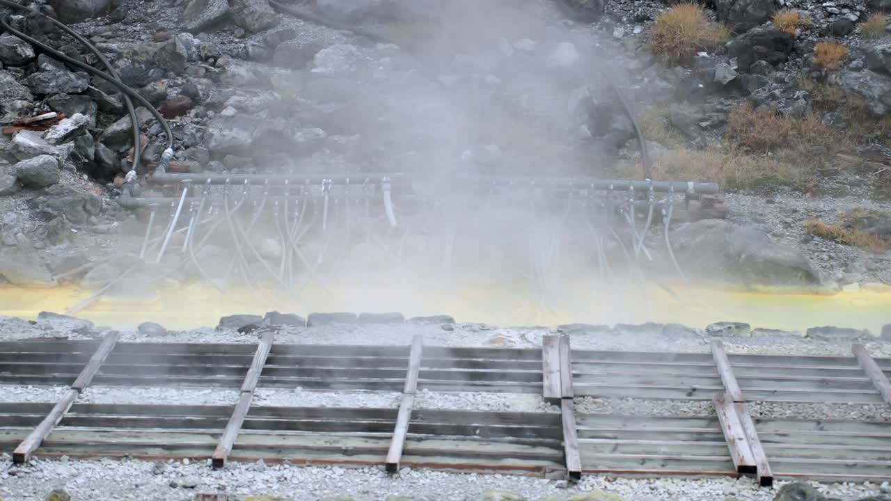 近距离拍摄的蒸汽从温泉附近的岩石山谷在秋田，日本东北。宁静的环境吸引游客在温泉附近放松，享受大自然的美丽，以及古老的硫磺生产过程视频素材