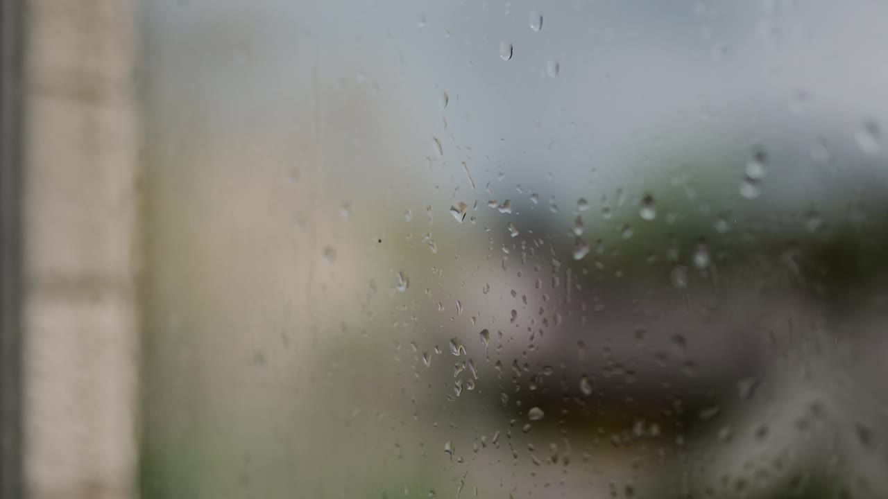 迷人的雨滴在下雨天优雅地从窗户倾泻而下，捕捉到宁静舒缓的氛围。视频下载