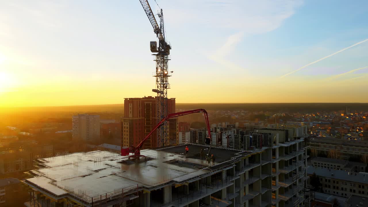 工人站在屋顶上浇筑混凝土的建筑物。日落时建筑工地的航拍照片。视频素材