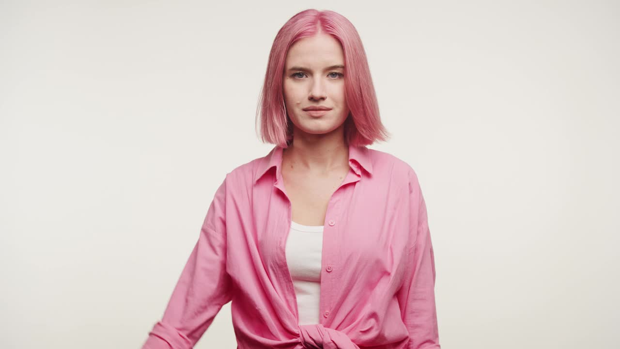 粉色头发的女人在白色背景上表现出不喜欢的姿态视频素材