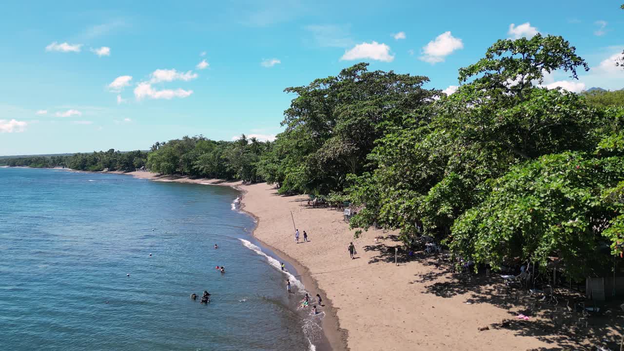 在热带岛屿上，海浪拍打着沙滩和游客视频素材